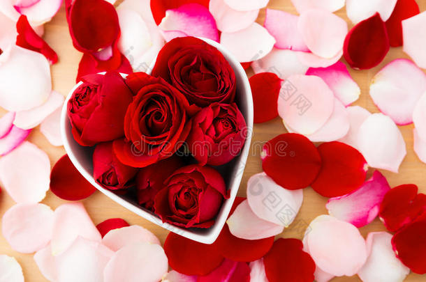 心形碗内有美丽的红玫瑰，旁边有花瓣