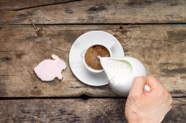 在白咖啡杯里倒牛奶。木底姜饼兔咖啡。