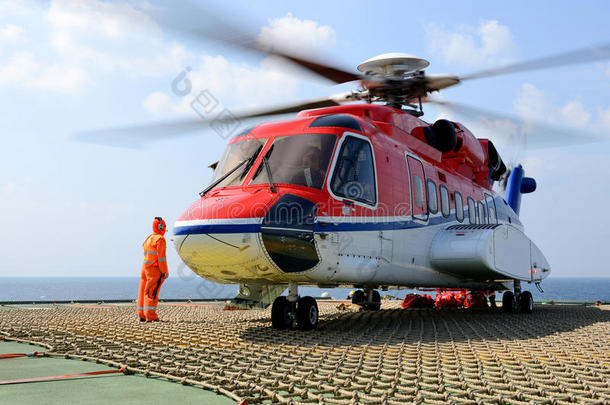 直升机着陆官小心地把行李装到石油钻塔的直升机上