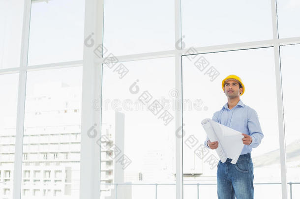 戴黄色安全帽的年轻建筑师，办公室有平面图