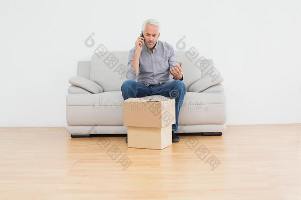 成熟男人在沙发上用cellpone在家里放盒子