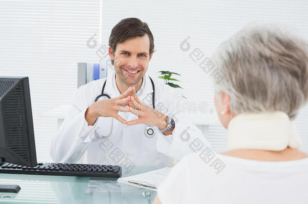 微笑的医生在医务室听老年病人讲话