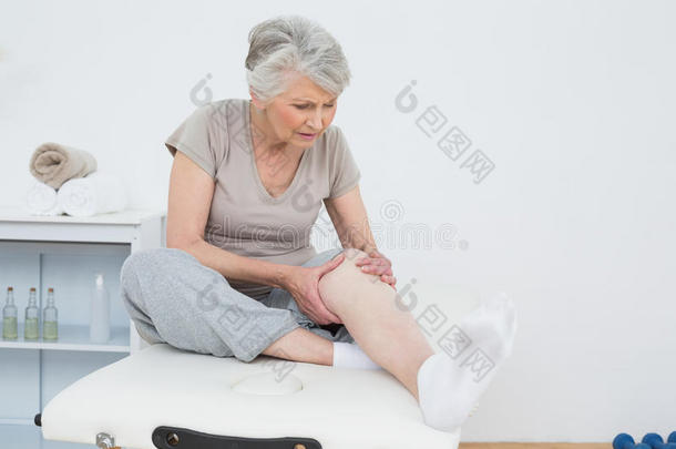 手放在疼痛的膝盖上的老妇人