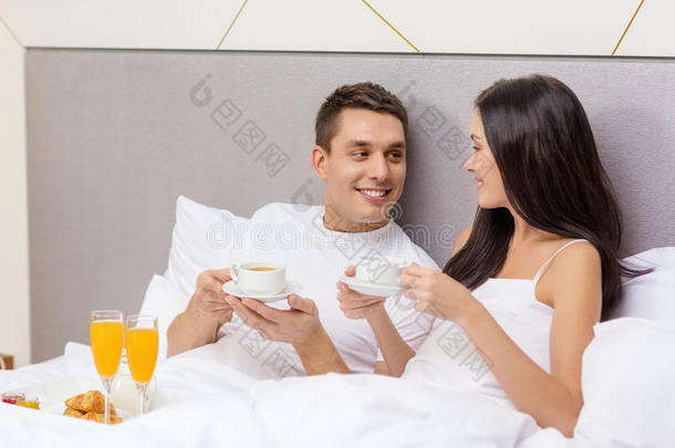 微笑的夫妇在<strong>酒店</strong>的床上吃<strong>早餐</strong>