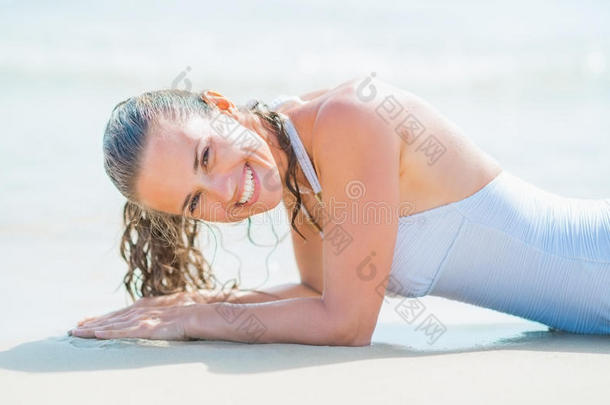 身穿泳衣的微笑少女躺在海边的画像