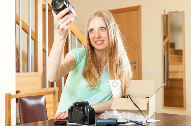 快乐的年轻可爱的女人在家里打<strong>开新</strong>的数码相机