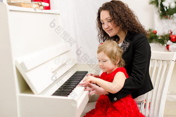母女俩在白钢琴上演奏