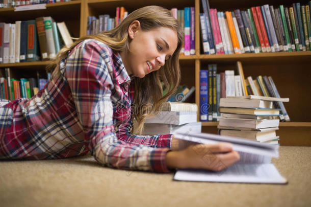 微笑的学生躺在<strong>图书馆</strong>地板上<strong>看书</strong>