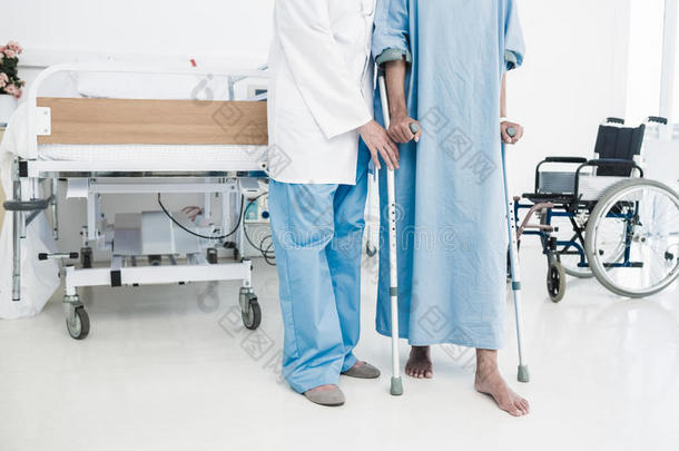 医生在医院帮助拄着拐杖的病人