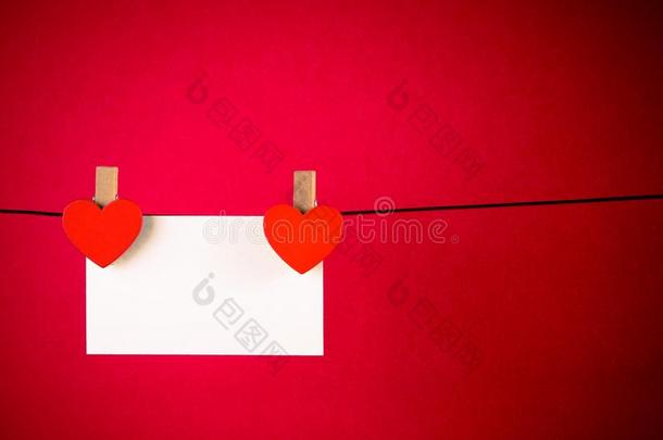红色背景上挂着贺卡的装饰红心，情人节的概念
