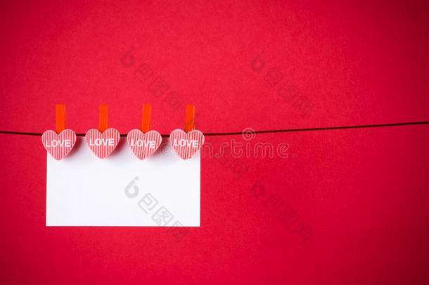 红色背景上挂着贺卡的<strong>装饰红心</strong>，情人节的概念