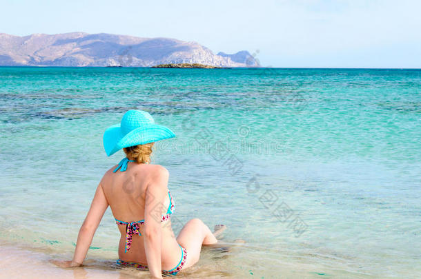 穿着<strong>泳装</strong>，戴太阳帽，在阳光明媚的<strong>海滩</strong>上放松的美丽年轻女子
