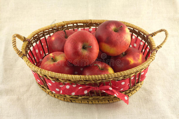 成熟的红苹果，棕色长柳条篮，米色布
