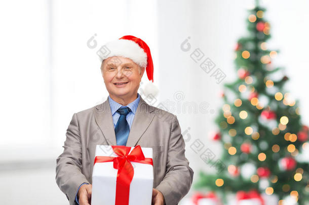 微笑的西装革履的男人和圣诞老人的帽子和礼物