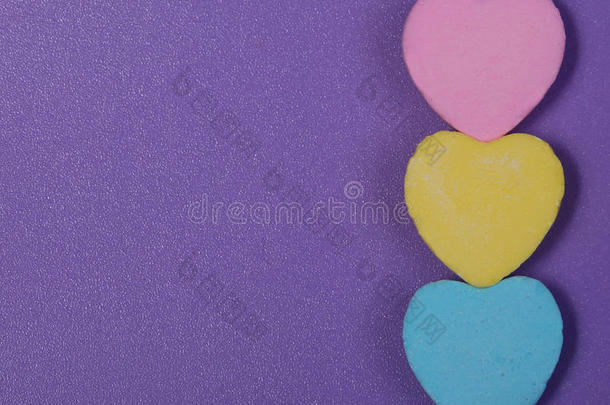 五彩缤纷的心。紫色背景上的三颗甜心糖