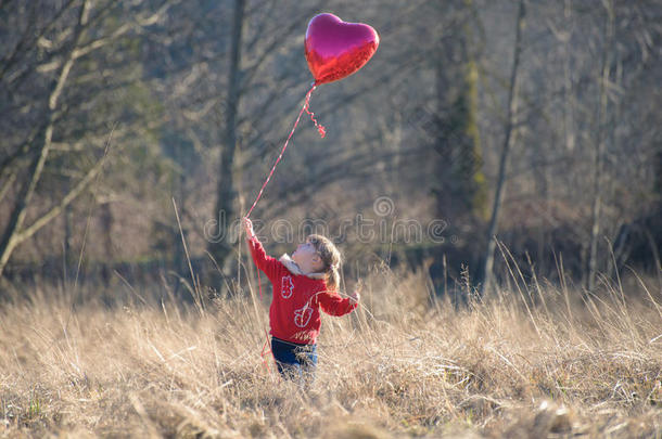 小女孩抬头看着心形气球