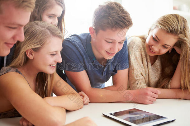 一群青少年聚集在数码平板电脑周围
