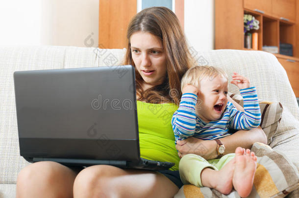 年轻妈妈带着哭闹的宝宝在网上工作