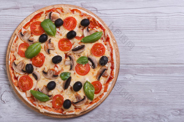 蘑菇披萨，桌上有橄榄、西红柿和罗勒