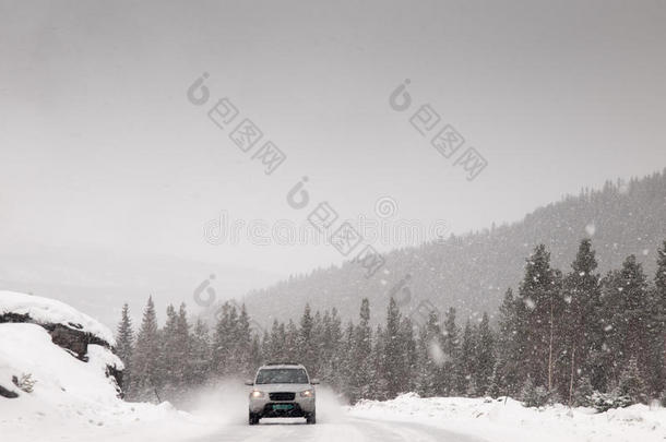 汽车在暴风雪中沿着积雪的道路行驶