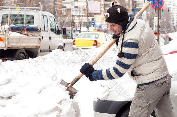 一个人用铲子在车旁铲雪