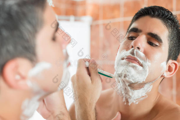 年轻的西班牙裔男子刮胡子
