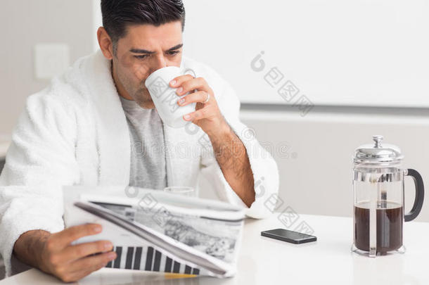 男人在厨房边看报纸边喝咖啡