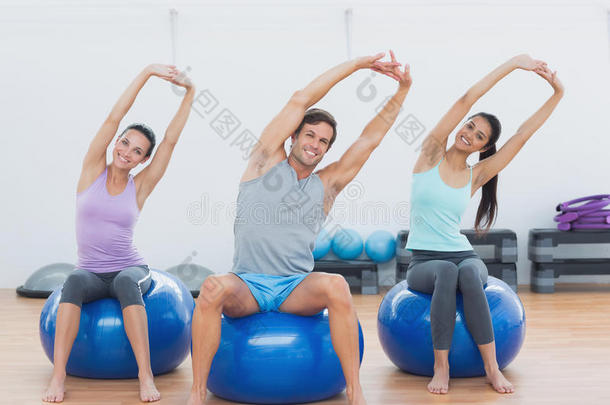 运动型的人在健身房把手伸到健身球上