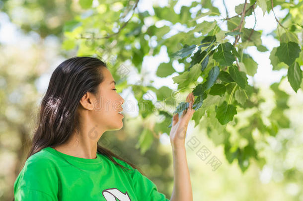 公园里穿着绿色环保t恤的女人闻到树叶的味道