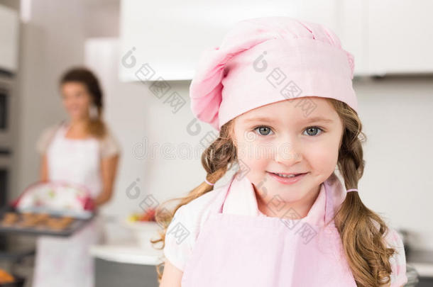 戴着<strong>粉色</strong>围裙和厨师帽的小女孩对着镜头<strong>微</strong>笑