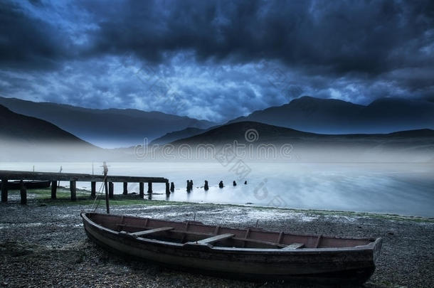 湖边的老船，湖水朦胧，<strong>山峦叠嶂</strong>，天空狂风暴雨