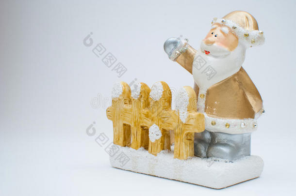 金色的圣诞老人雕像，站在花园篱笆后，一只手挥舞，在摄影棚拍摄