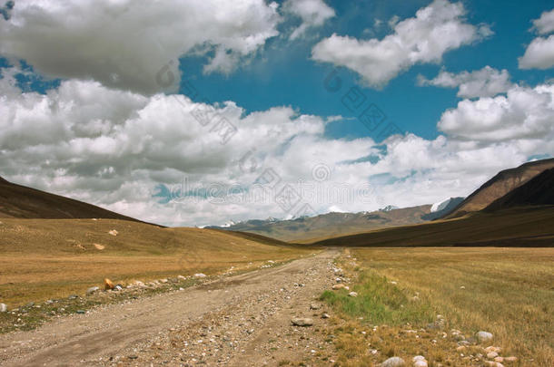 中亚山脉之间的乡村公路，在雷雨来临前天空中有一阵乌云