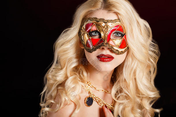 一位年轻漂亮的金发女郎的肖像，深色背景下，脸上戴着戏剧面具