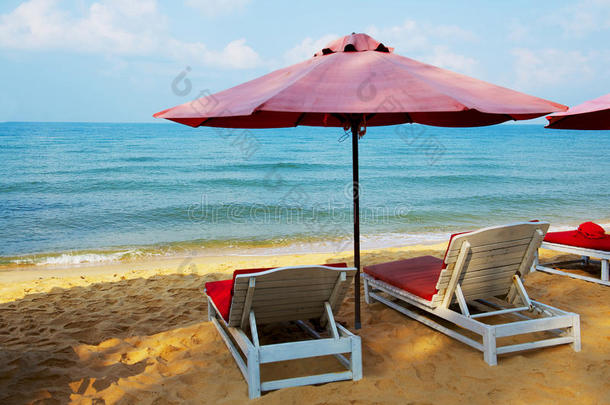 海滩上的白色日光浴床和雨伞
