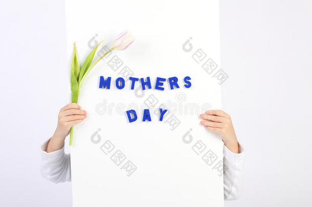 两只童年的手拿着白板，上面写着蓝色的母亲节，还有一只白色和紫色的郁金香