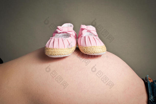 婴儿第一双鞋搁在怀孕的肿块上