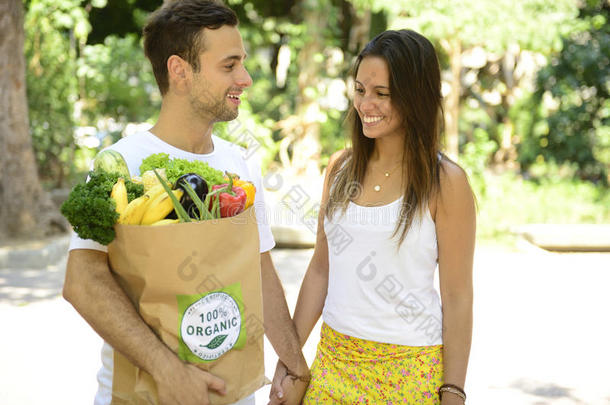 这对幸福的夫妇<strong>拎</strong>着一个装满有机蔬菜和水果的回收纸<strong>袋</strong>。