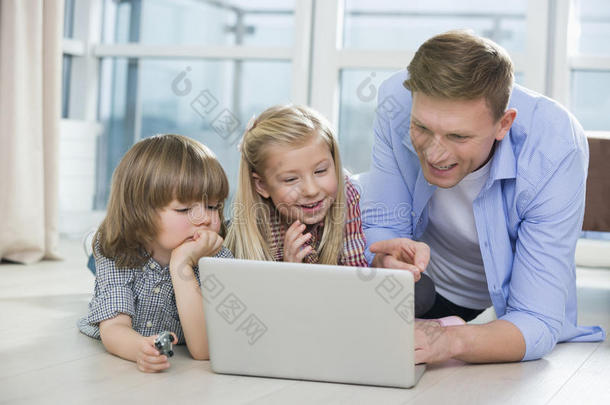 快乐的父亲在家里用笔记本电脑给孩子们看东西