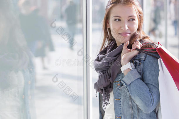 站在商店旁边的女人提着购物袋