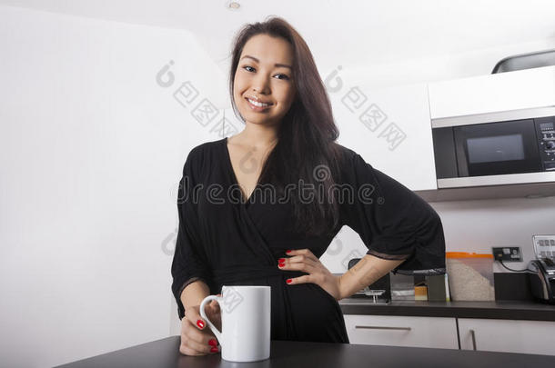 年轻漂亮女人在厨房喝咖啡的画像