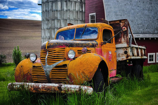 红色谷仓前的一辆老式报废卡车