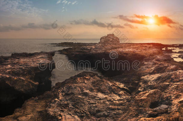 夕阳西下的大海和岩石海岸与古老的遗迹