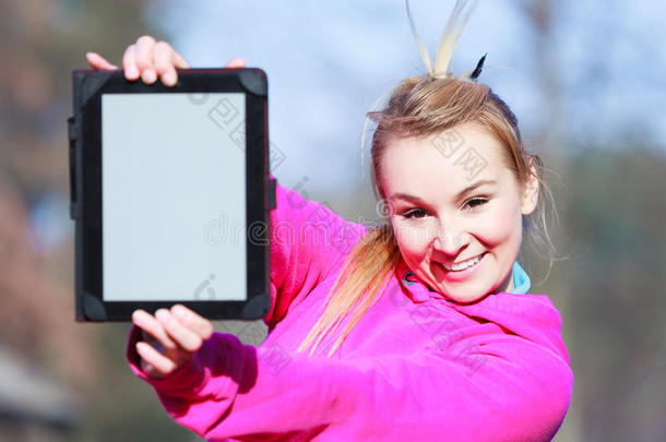 身穿粉色运动服的少女在户外展示空白平板电脑