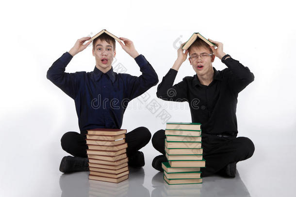 两个十几岁的男孩头上顶着书