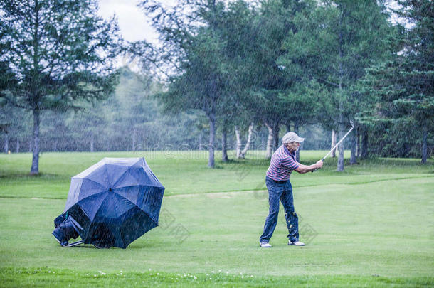 雨天高尔夫球手在球道上<strong>挥杆</strong>击球
