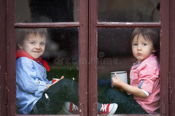 两个男孩在窗边笑边喝茶