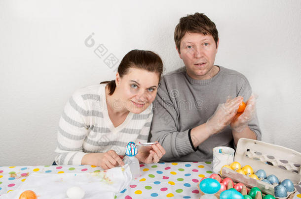 一对夫妇在室内的桌子上装饰复活节彩蛋。