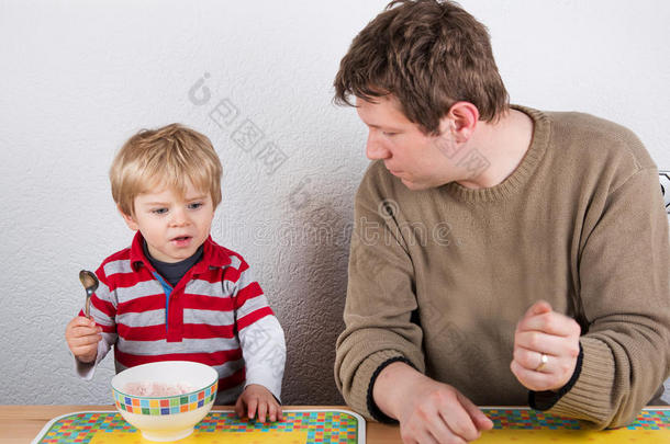 年轻的<strong>父亲和</strong>小<strong>儿子在家里</strong>的厨房吃饭。