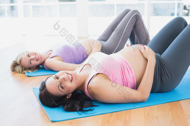 瑜伽课上微笑的孕妇躺在垫子上